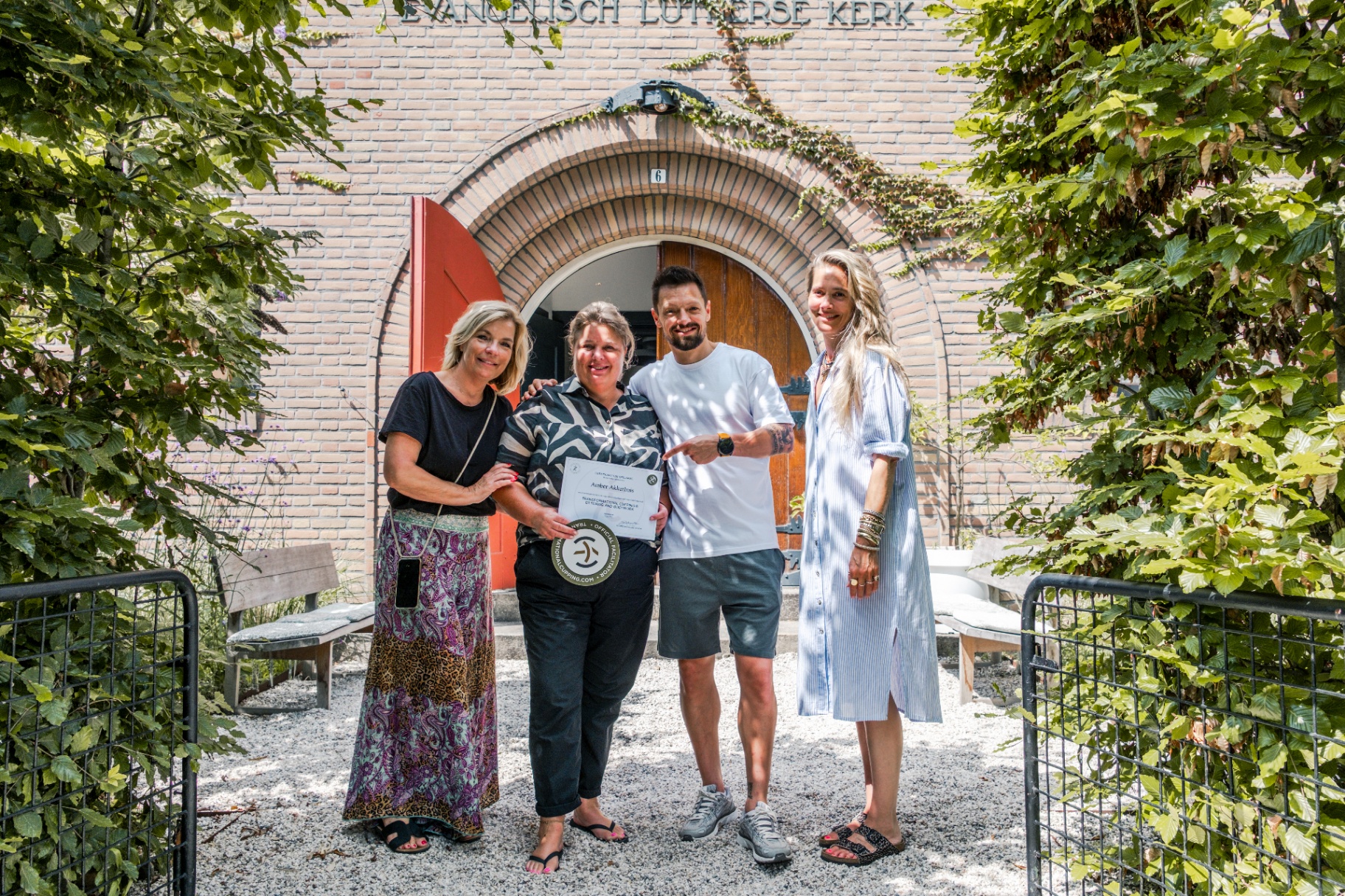 Gecertificeerde cursist met docenten voor de entree van de Evangelisch Lutherse Kerk in Hilversum.